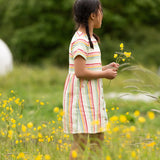 A child wearing the Little Green Radicals cream rainbow striped short sleeve button front dress.