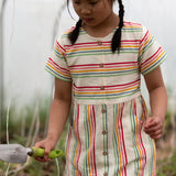 A child wearing the Little Green Radicals cream rainbow striped short sleeve button front dress.