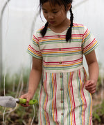 A child wearing the Little Green Radicals cream rainbow striped short sleeve button front dress.