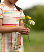 A close up of the button up front on the Little Green Radicals children's cream rainbow striped short sleeve dress being worn by a child.