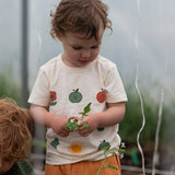 Close up of the nature illustrations on the front of the Little Green Radicals cream vintage style kids organic cotton t-shirt being worn with peach shorts.