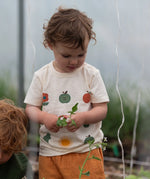 Close up of the nature illustrations on the front of the Little Green Radicals cream vintage style kids organic cotton t-shirt being worn with peach shorts.