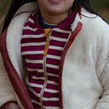 Child wearing a Little Green Radicals cream zip up cosy recycled fleece jacket with the zip open.