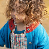 A close up of a child wearing the  Little Green Radicals From One To Another Deep Blue Colour Block Knitted Cardigan. This organic cotton cardigan is part of a wide range of organic cotton, Fairtrade children's clothing and outerwear available here at Babipur.