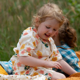 Child wearing the Little Green Radicals organic cotton short pyjamas set in cream with a pink and yellow flora print. 