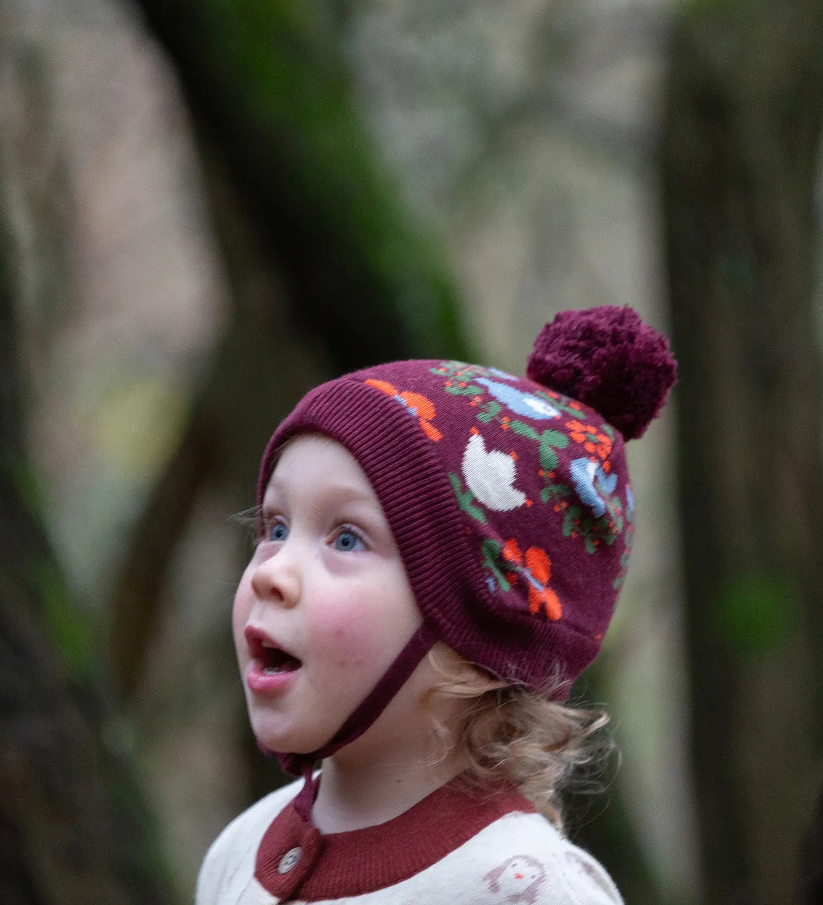Child wearing the Little Green Radicals folk birds knitted purple bobble hat.