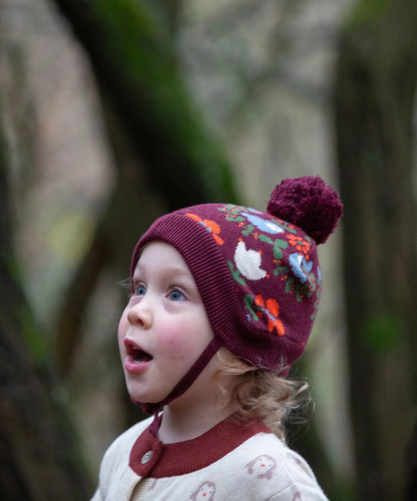 Child wearing the Little Green Radicals folk birds knitted purple bobble hat.