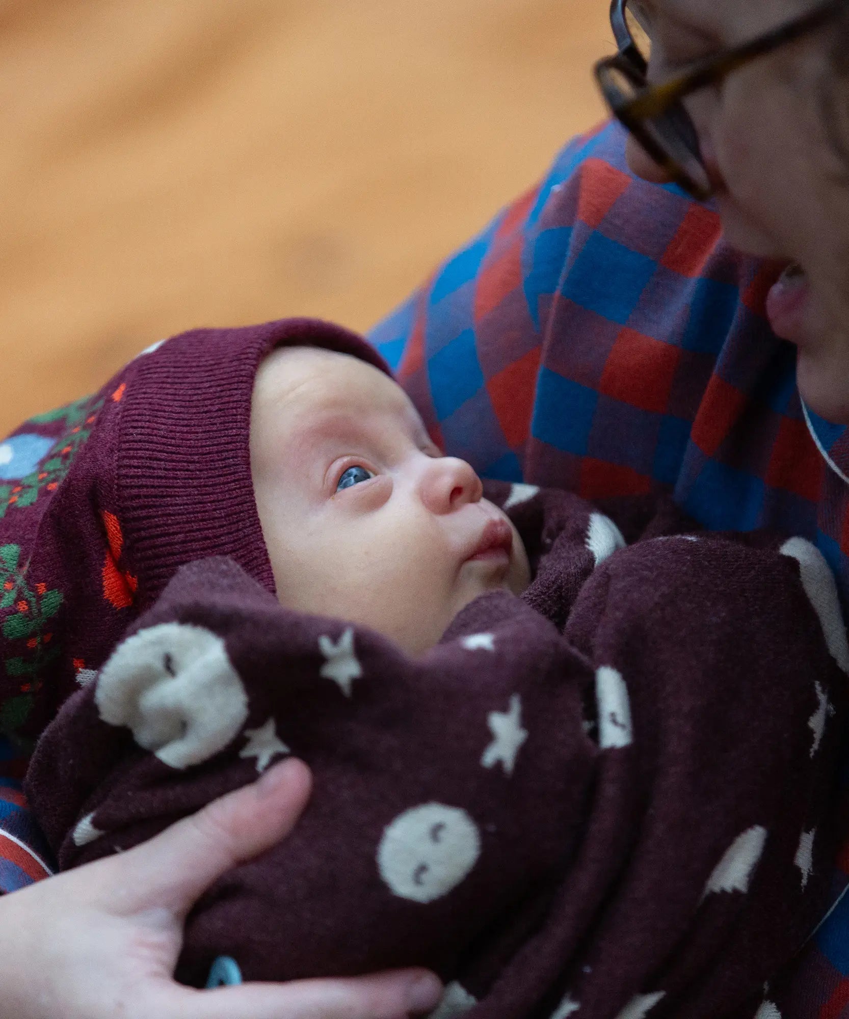 Young babywearing the Little Green Radicals folk birds knitted purple bobble hat.