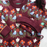 Little Green Radicals Folk Birds knitted jumper and hat placed on a white surface.