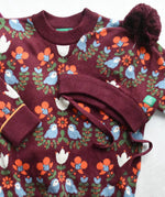 Little Green Radicals Folk Birds knitted jumper and hat placed on a white surface.