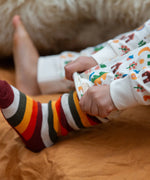 Child wearing the rainbow striped socks from the Little Green Radicals folk tales ankle socks 3 pack.