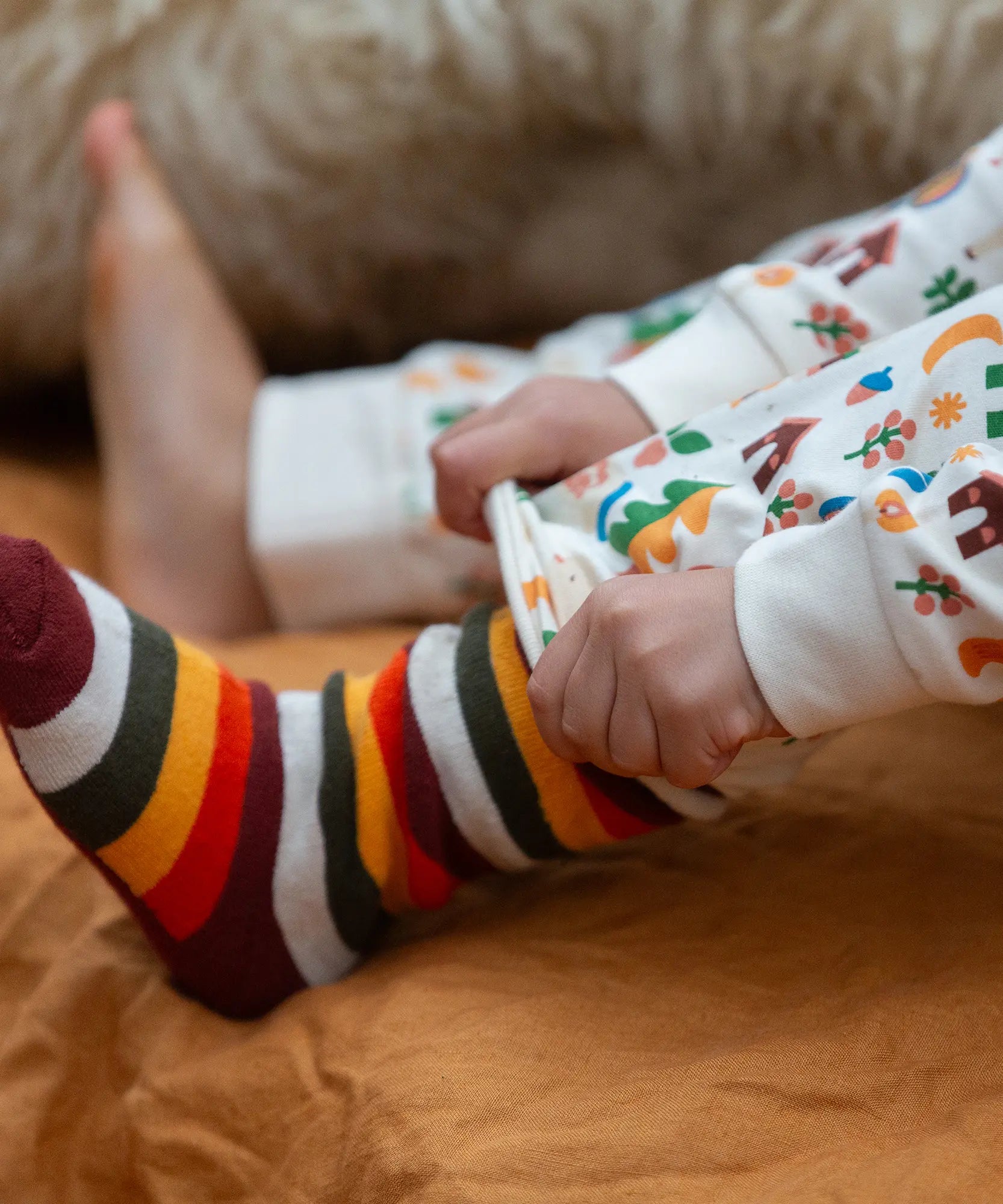 Child wearing the rainbow striped socks from the Little Green Radicals folk tales ankle socks 3 pack.