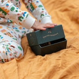 Child holding the green gift box packaging that the Little Green Radicals folk tales ankle socks 3 pack comes in.