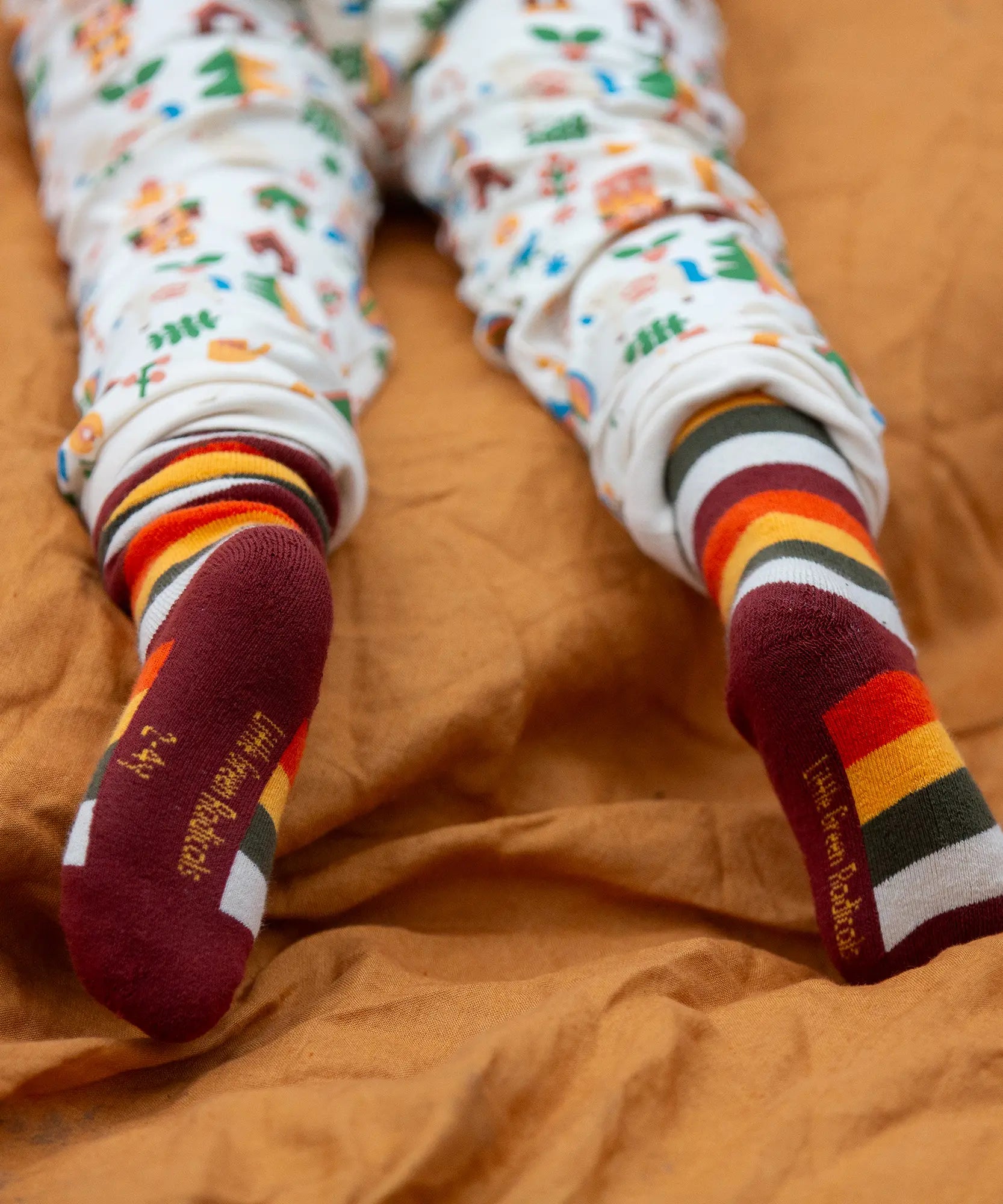 Child wearing the rainbow striped socks from the Little Green Radicals folk tales ankle socks 3 pack.