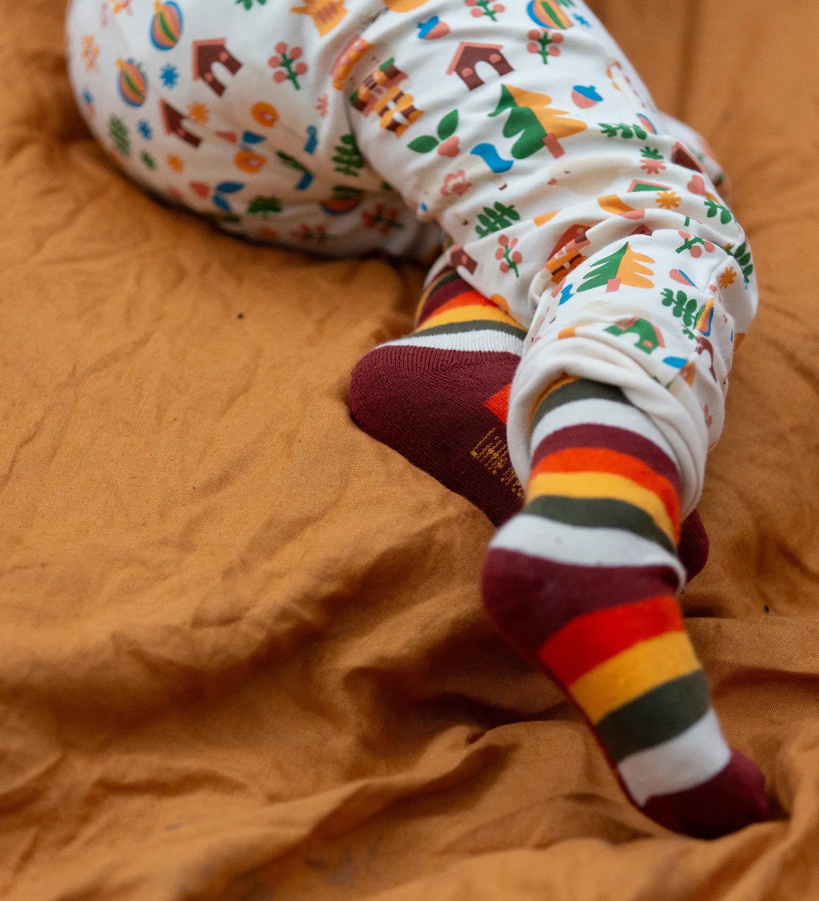 Child wearing the rainbow striped socks from the Little Green Radicals folk tales ankle socks 3 pack.