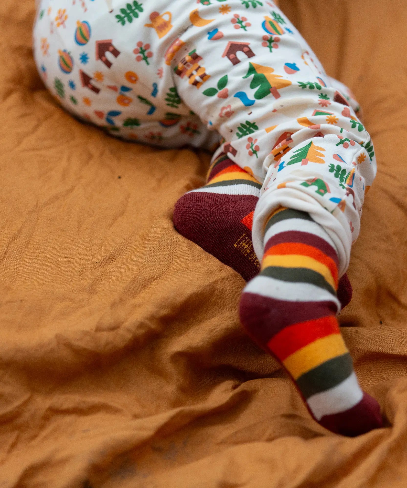 Child wearing the rainbow striped socks from the Little Green Radicals folk tales ankle socks 3 pack.