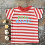 A child holding a piece or dark wood in their hand and wearing the Little Green Radicals Free Range Top