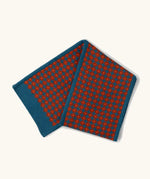 Little Green Radicals ginger squares design knitted scarf. Blue with ginger red squares pattern over it.