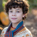 Child wearing a Little Green Radicals  ginger squares knitted scarf with a knitted jumper. 