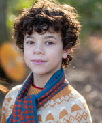 Child wearing a Little Green Radicals  ginger squares knitted scarf with a knitted jumper. 