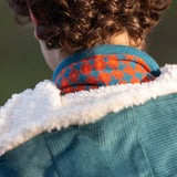 Child wearing a Little Green Radicals  ginger squares knitted scarf with a corduroy coat, view of back.