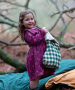 Child wearing the Little Green Radicals pink flowers sailor dress in purple with green wellington boots. 