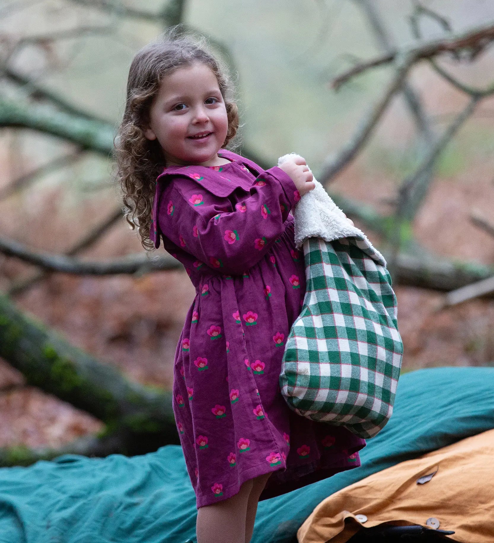 Child wearing the Little Green Radicals pink flowers sailor dress in purple with green wellington boots. 