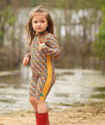 A child wearing the Little Green Radicals Vintage Flowers UPF 50+ Recycled Sunsafe Sunsuit with a pair of red wellington boots.
