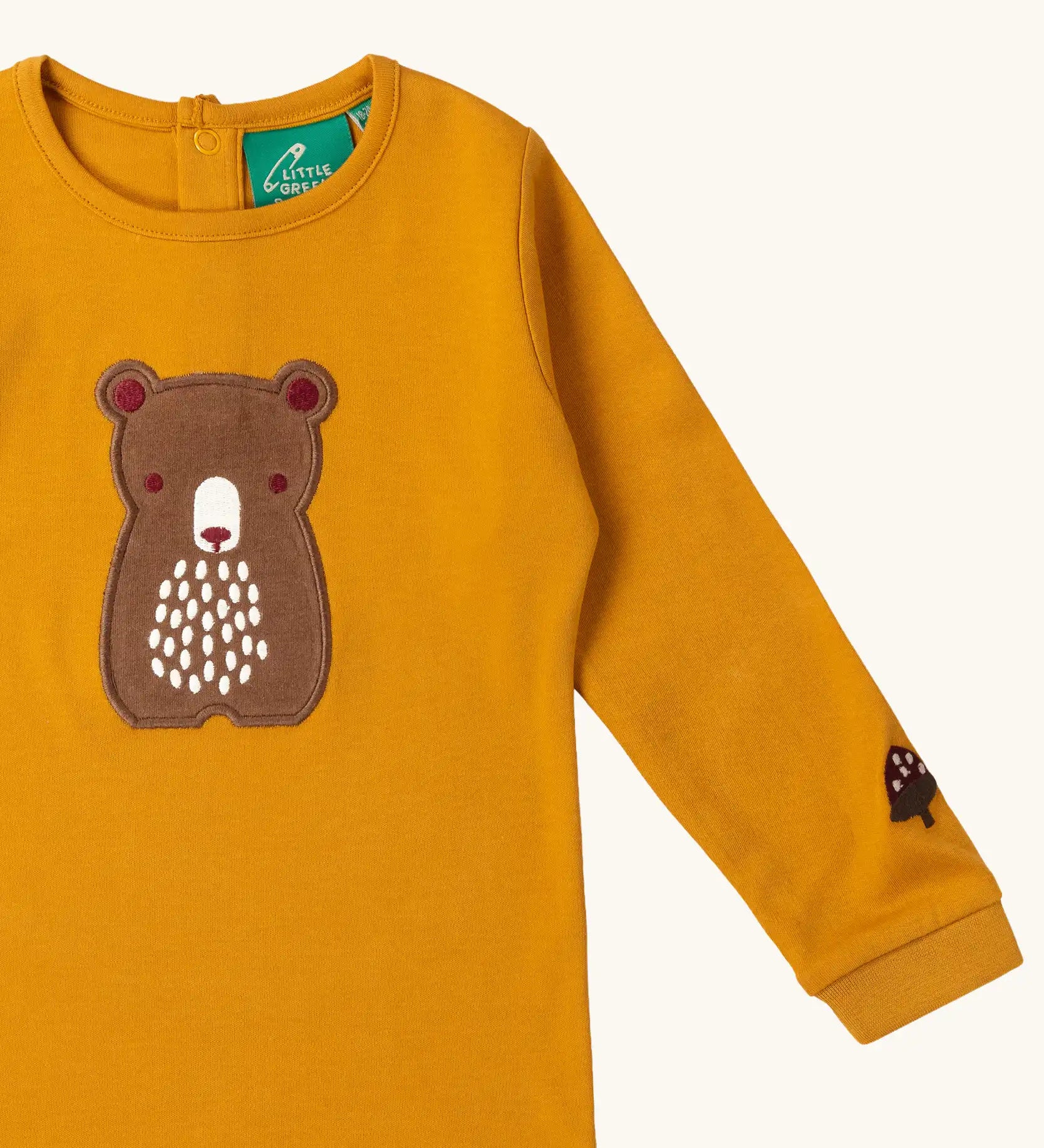 Close up of the bear applique on the front of the Little Green Radicals gold bear applique organic cotton long sleeve childrens top.