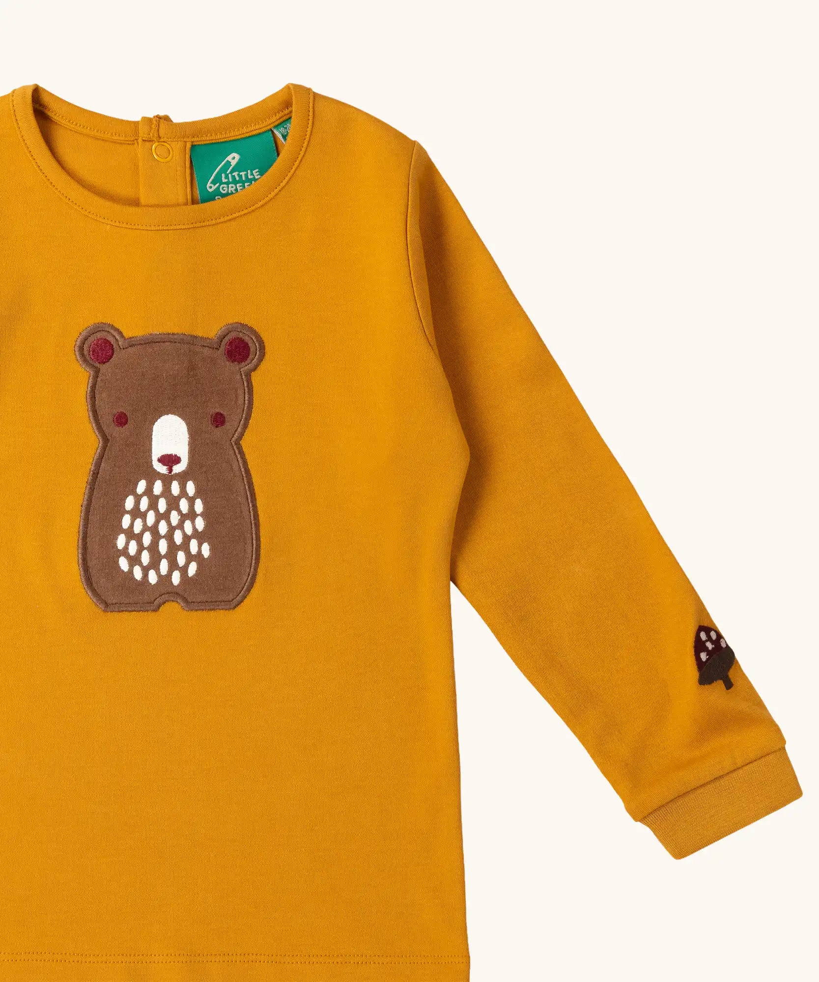 Close up of the bear applique on the front of the Little Green Radicals gold bear applique organic cotton long sleeve childrens top.