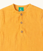Close up of the button up front on the Little Green Radicals golden ochre yellow organic muslin cotton short sleeve kids top.