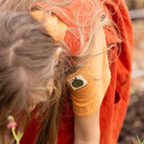 Close up of the green apple tage details on the side of the sleeve of the Little Green Radicals children's golden ochre yellow short sleeved henley top.
