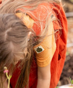 Close up of the green apple tage details on the side of the sleeve of the Little Green Radicals children's golden ochre yellow short sleeved henley top.
