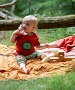 Child wearing the Little Green Radicals green apple applique organic short sleeve red t-shirt with cherry knee patch joggers.