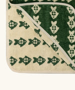 Little Green Radical hooded towel in green with a repeating fish design showing contrast cream inner lining 