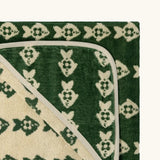 Top corner of Little Green Radicals GOTS organic cotton hooded towel in green and cream with a repeating fish design