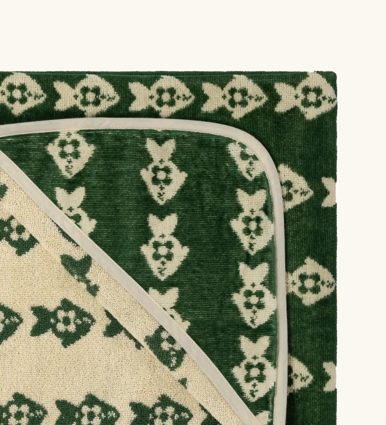 Top corner of Little Green Radicals GOTS organic cotton hooded towel in green and cream with a repeating fish design