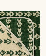 Top corner of Little Green Radicals GOTS organic cotton hooded towel in green and cream with a repeating fish design