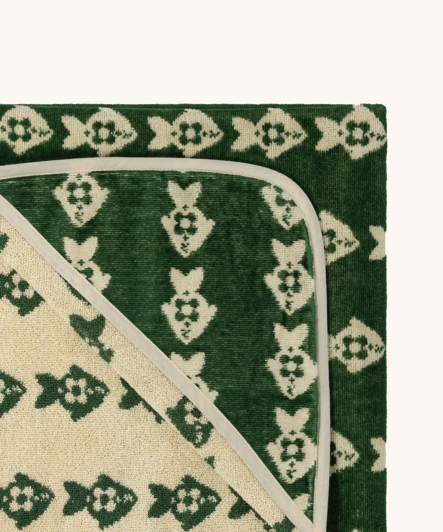 Top corner of Little Green Radicals GOTS organic cotton hooded towel in green and cream with a repeating fish design