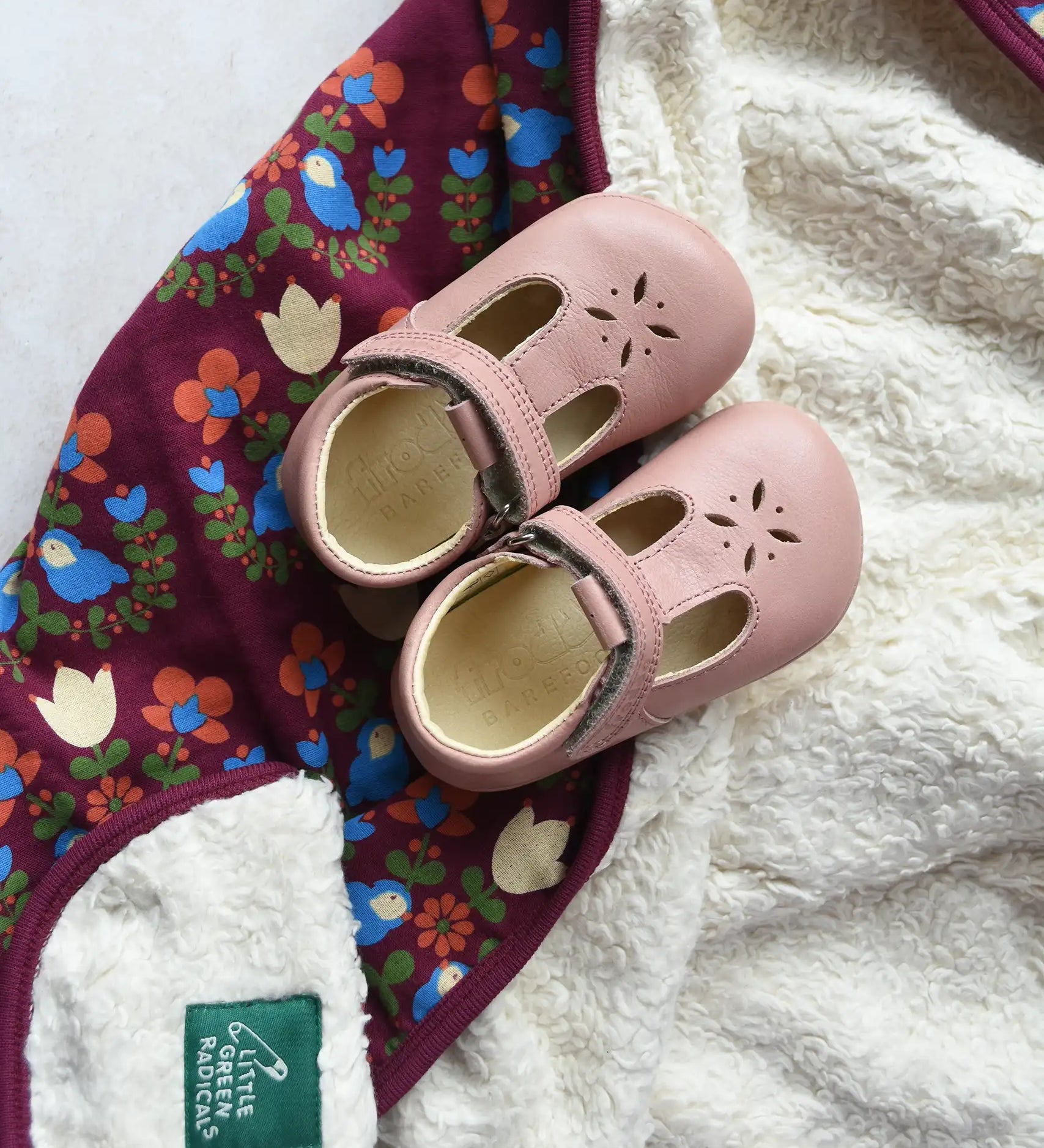 Little Green Radicals folk bird organic cotton hooded baby blanket with sherpa fleece lining with a pair of pink Froddo barefoot shoes p[laced on top.