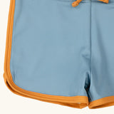 Close up of the yellow gold binding on the Little Green Radicals hazy blue kids swim shorts.