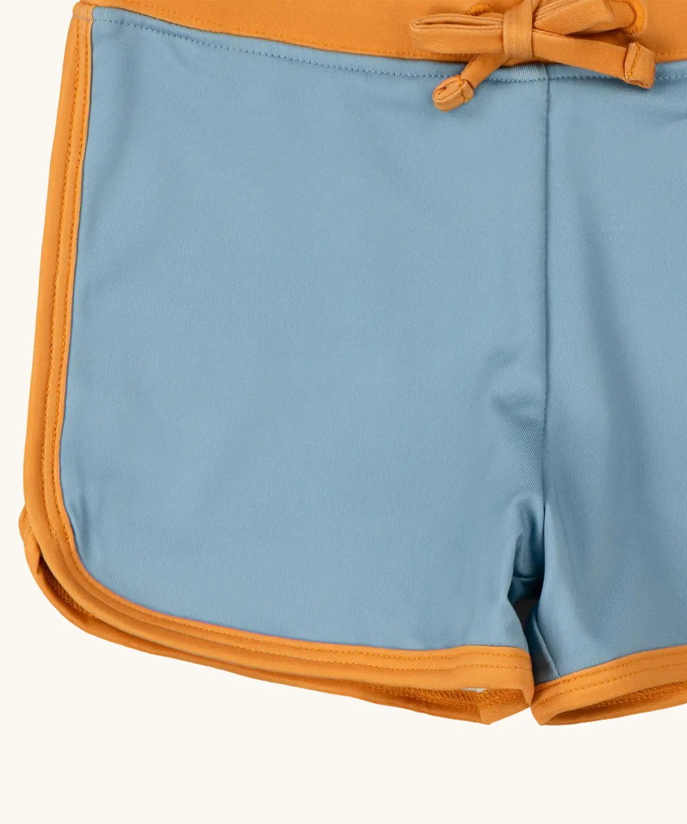 Close up of the yellow gold binding on the Little Green Radicals hazy blue kids swim shorts.
