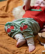 Close up of the red cherry knee appliques on the Little Green Radicals cherry knee patch green cream striped organic cotton joggers being worn.