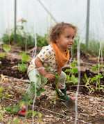 Little Green Radicals vintage style rainbows organic cotton t-shirt & jogger playset being worn. A repeat pattern top featuring nature themed illustrations with cream rainbow striped trousers.