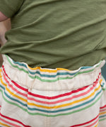 Close up of the elasticated waist on the Little Green Radicals children's cream rainbow striped by the sea twill shorts being worn. 