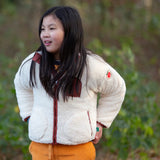 Child wearing a Little Green Radicals cream zip up cosy recycled fleece jacket.