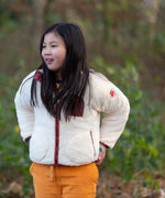 Child wearing a Little Green Radicals cream zip up cosy recycled fleece jacket.