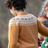 Back of a child wearing the Little Green Radicals mountain Fair Isle snuggly woollen jumper in yellow gold. The Fair Isle details are around the neckline featuring snow topped mountains surrounded by patterns.