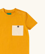 Close up of the buttoned chest pocket on the Little Green Radicals golden ochre yellow short sleeve essential short sleeve, organic cotton t-shirt. 