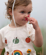 Close up of the nature illustrations on the front of the Little Green Radicals cream vintage style kids organic cotton t-shirt being worn.